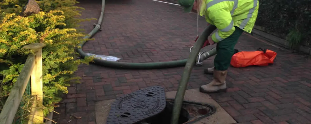 Septic tank cleaning technician servicing a septic tank with a vacuum hose in Harrisburg, PA