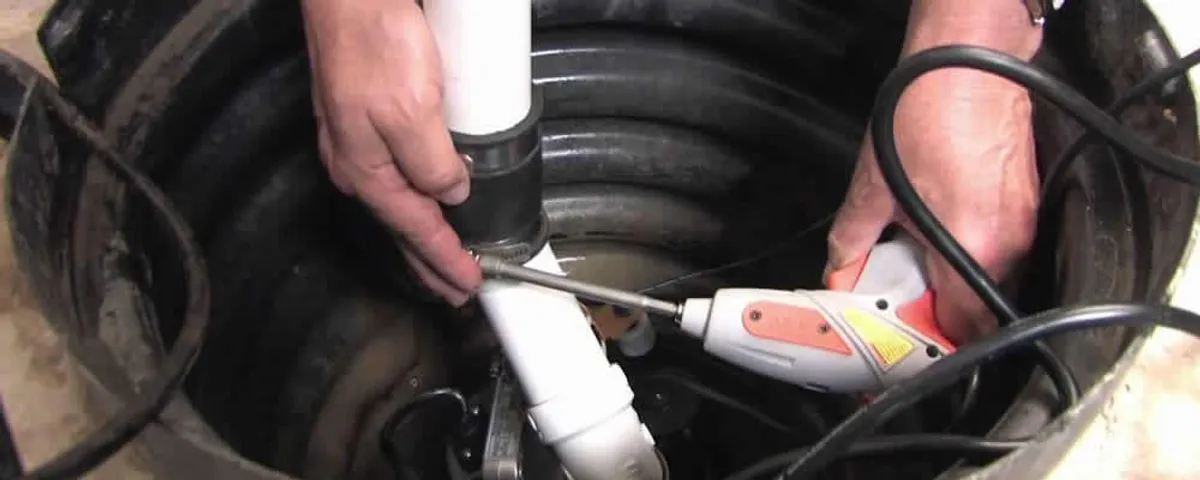 Sump pump installation technician connecting PVC discharge piping in Harrisburg, PA